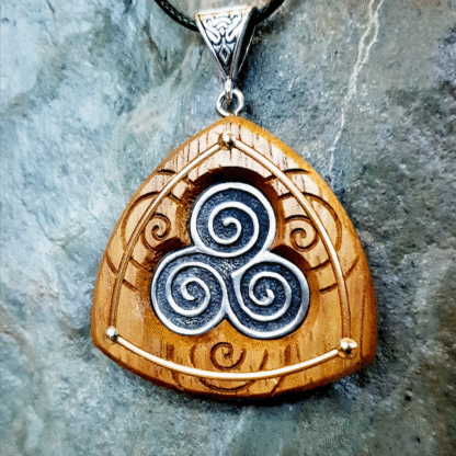 Classic Handmade Triskele Necklace in fine pewter on Iroko with background of spirals