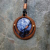 Cabochon of Blue Sodalite mounted in an Iroko textured wood bezel and decorated with bright copper accents & inky blue spirals.