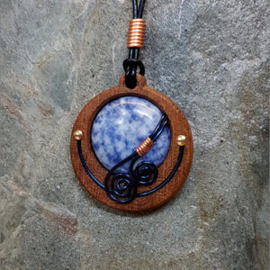 Cabochon of Blue Sodalite mounted in an Iroko textured wood bezel and decorated with bright copper accents & inky blue spirals.