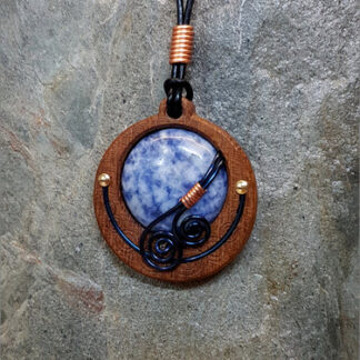Cabochon of Blue Sodalite mounted in an Iroko textured wood bezel and decorated with bright copper accents & inky blue spirals.